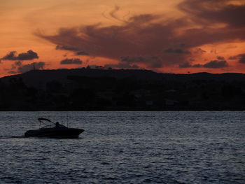 Silhouette boat in sea against sky during sunset