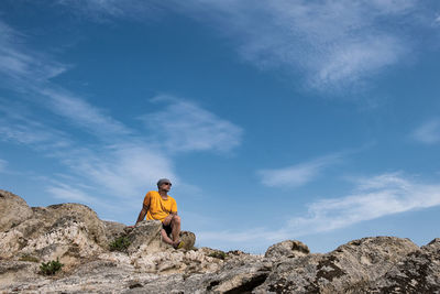 Low angle view of man on rock against sky