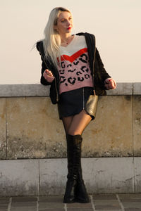 Full length of woman standing against wall