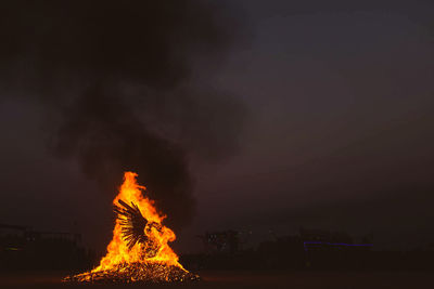 Bonfire on field against sky at night