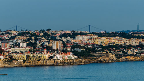 Aerial view of townscape by sea against clear sky