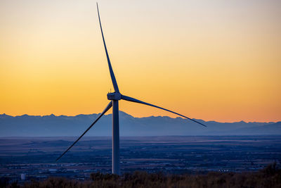 Wind turbines in a field with clear sky at sunset