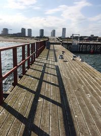 Pier over river in city against sky