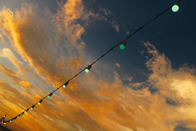 Low angle view of street lights against dramatic sky