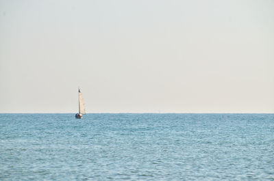 Sailboat in sea against clear sky