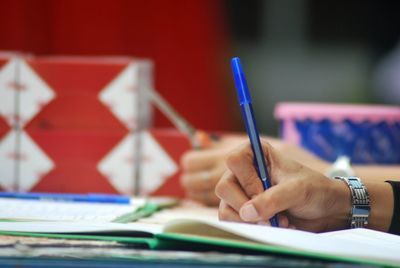 Cropped image of hand writing in book on table