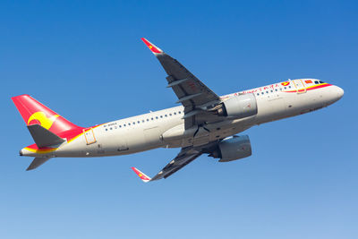 Low angle view of airplane flying against clear blue sky