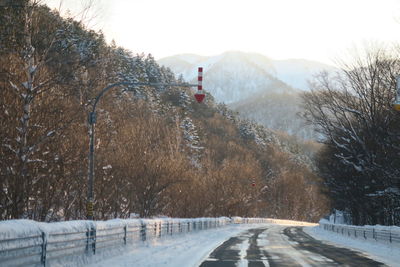 Road amidst trees against sky during winter