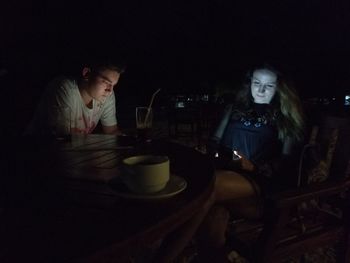 Young woman using phone while sitting on table