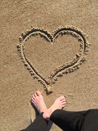 Low section of person with heart shape on sand