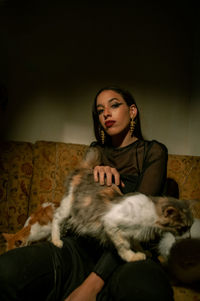 Portrait of woman sitting with cats on sofa at home