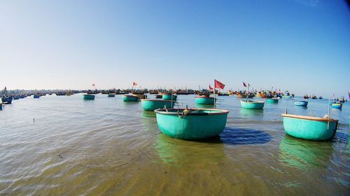Boats in sea against clear blue sky