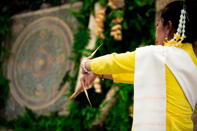 Midsection of man holding yellow umbrella on temple