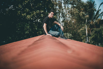 Full length portrait of young man sitting on land