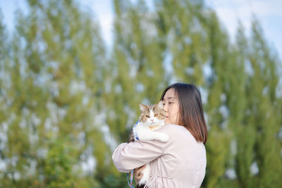 Woman embracing cat outdoors