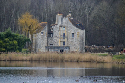 Houses by lake and trees in forest