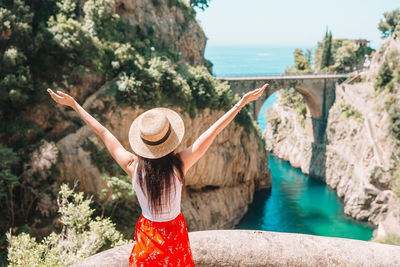 Rear view of woman standing by bridge over river