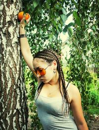 Young woman against tree trunk