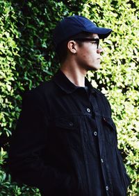 Young man standing against plant