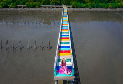 Woman sitting over lake on colorful footbridge