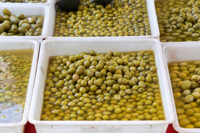 Green olives with water in container for sale at market