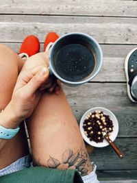 Low section of woman holding coffee on table