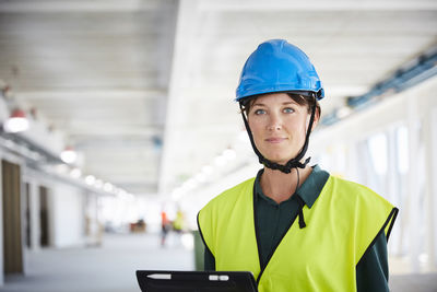 Portrait of confident female construction manager in reflective clothing at site