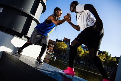 Men jumping in city against sky