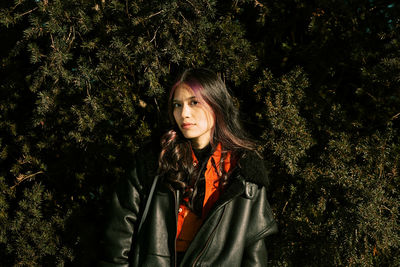 Portrait of woman standing by tree against plants