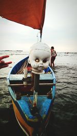 People in boat on sea shore against sky