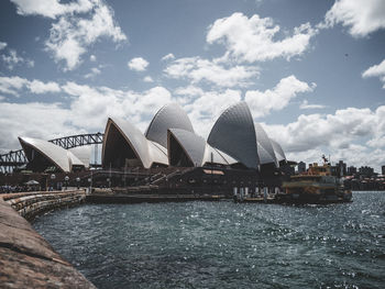 Arch bridge over river against cloudy sky