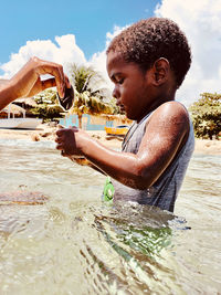 Portrait of boy holding starfish in water 