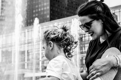 Smiling mother with daughter standing against building