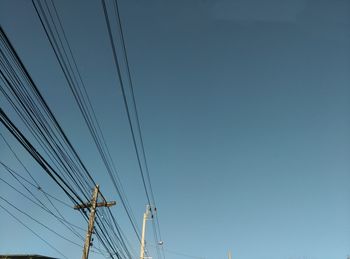 Low angle view of electricity pylon against blue sky