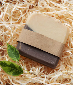 Assorted natural handmade soap bars and green leaves on a straw background
