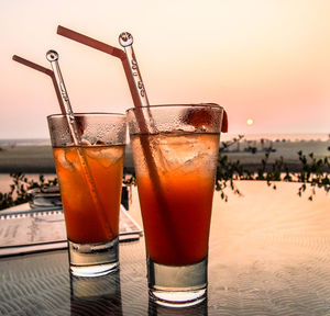 Close-up of drinks on table at sunset