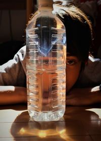 Close-up portrait of boy with water bottle on table