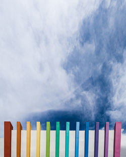 Row of multi colored fence against sky