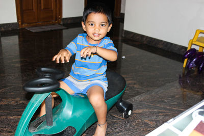 Portrait of smiling boy riding tricycle at home