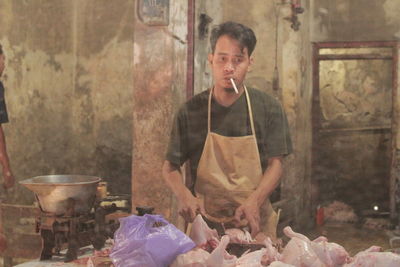 Portrait of butcher smoking cigarette while cutting meat