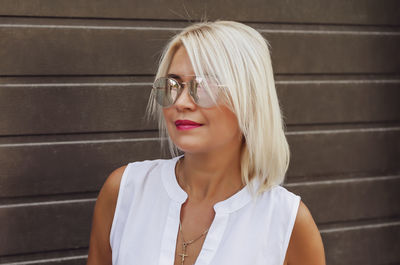 Portrait of blonde in sunglasses on background of brown blinds shutters garage house