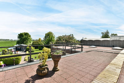 Rear view of woman sitting on retaining wall against sky