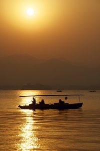 Boat sailing in sea at sunset