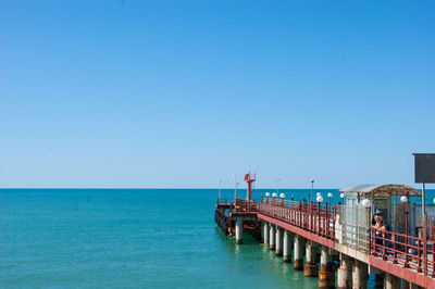 Pier over sea against clear blue sky