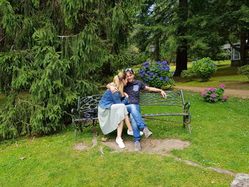 Rear view of women sitting on grass against trees