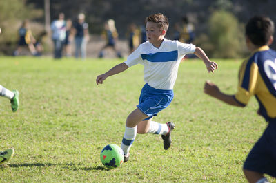 Teen soccer player dribbling ball through defenders