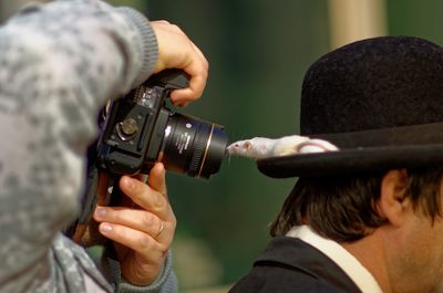Photographer photographing rat on cap worn by man