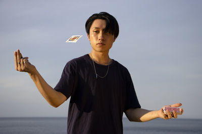 Full length of young man holding camera against sky