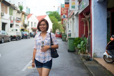 Smiling woman looking away while standing on street in city