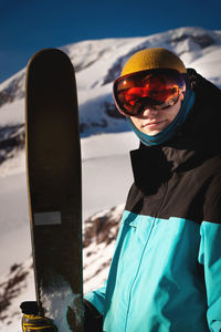 Happy man standing with skis in front of the mountains on a sunny day. young man smiling looking at